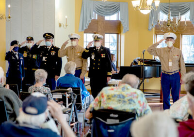 Military personnel salute in front of an audience of seniors